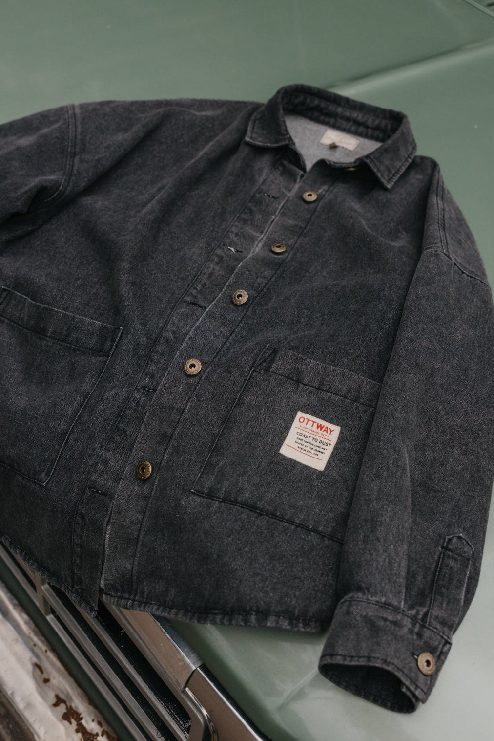 washed Dark denim jacket on a green car hood